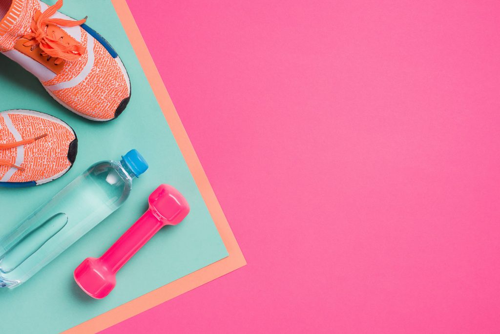 HIIT gym equipment for women over 50 laid out on bright pink background